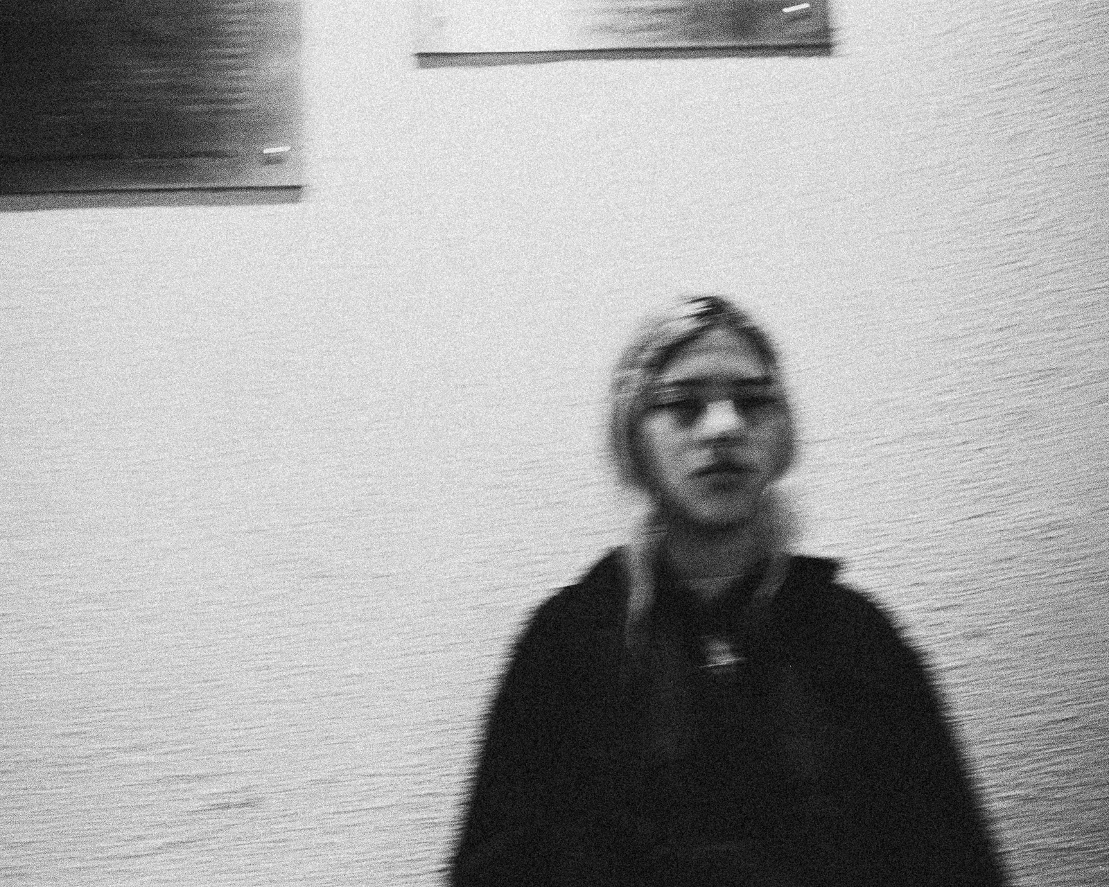 black-and-white blurred portrait against a light wall